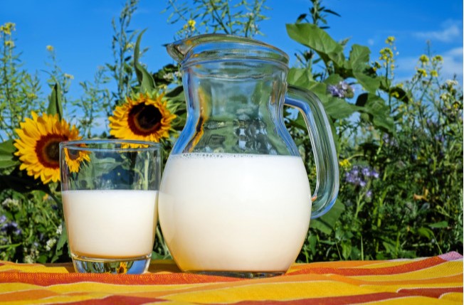 야외 테이블 위에 큰 병에 들어있는 우유 그리고 작은 병에 들어있는 우유